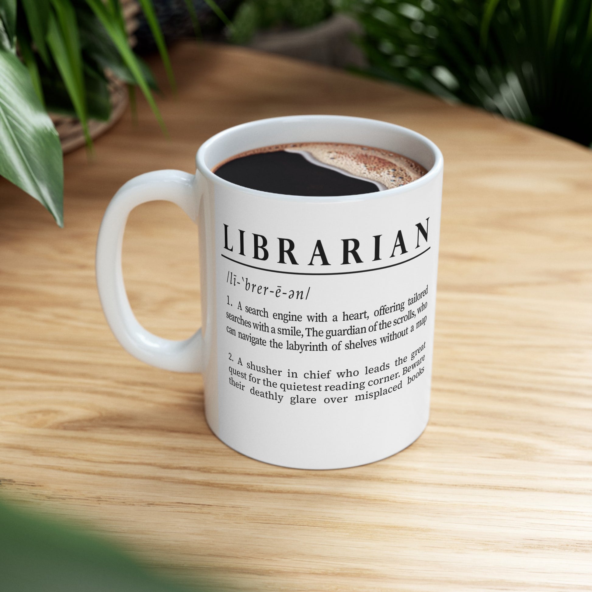 A sleek white ceramic mug presents a whimsical definition of 'Librarian', written in bold black font. The humorous text portrays a librarian as both a heartfelt search engine and a quiet corner seeker.