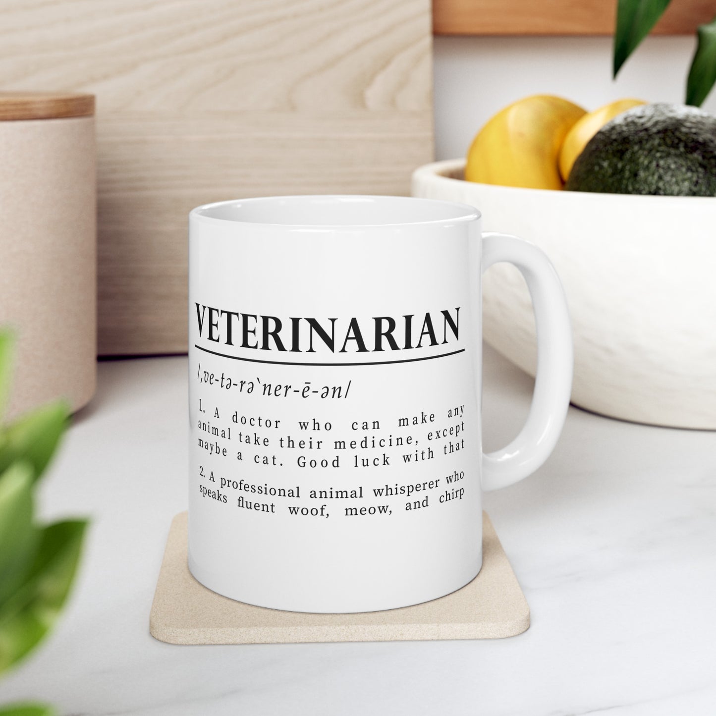 a white cup with bold black text on a plain white background defining 'Veterinarian'. The definition humorously mentions a vet's challenges with medicating animals, especially cats, and describes them as fluent in animal sounds.