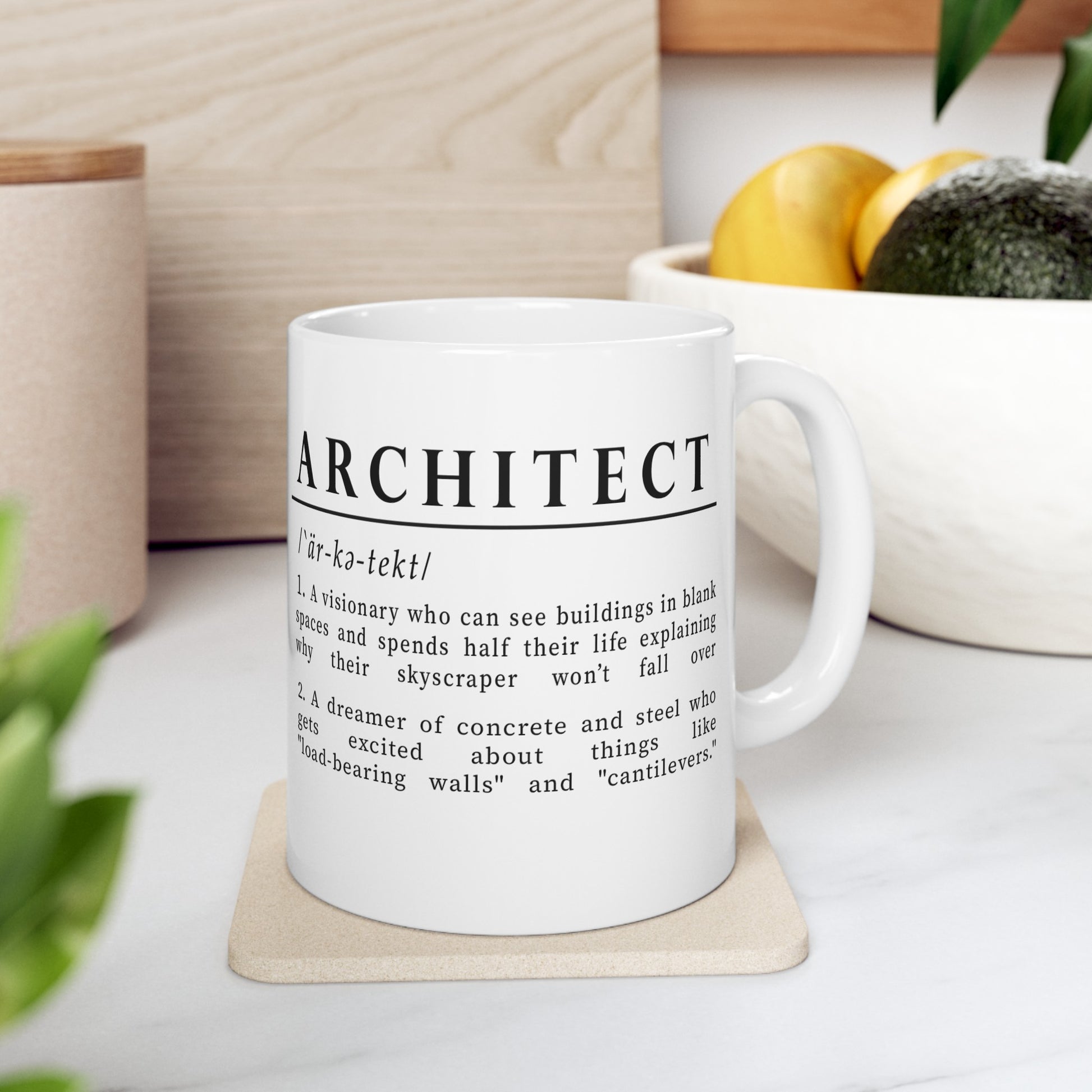 A white ceramic mug is adorned with a clever definition of 'Architect' in bold black text. The humorous definition describes architects as visionary planners and dreamers of concrete and steel, excited by structural elements like "load-bearing walls" and "cantilevers."