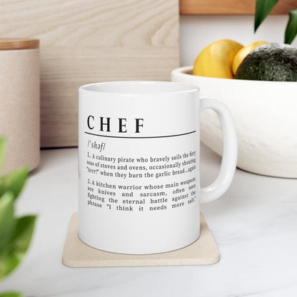 A white ceramic mug with a playful and humorous definition of 'Chef', printed in sharp black lettering. The text describes a chef as a culinary pirate and a kitchen warrior, humorously highlighting the challenges and quirks of culinary life. 