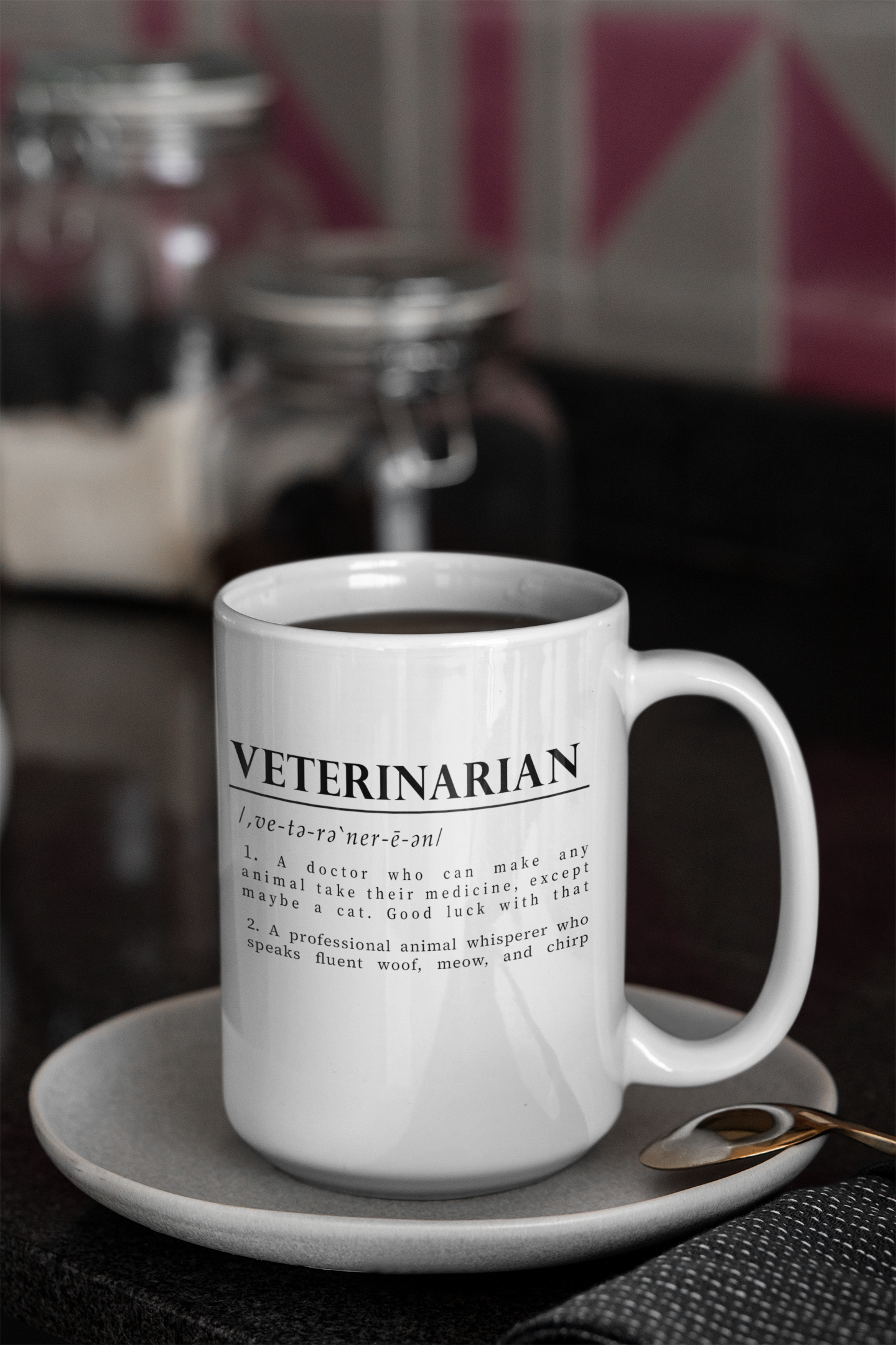 a white cup with bold black text on a plain white background defining 'Veterinarian'. The definition humorously mentions a vet's challenges with medicating animals, especially cats, and describes them as fluent in animal sounds.