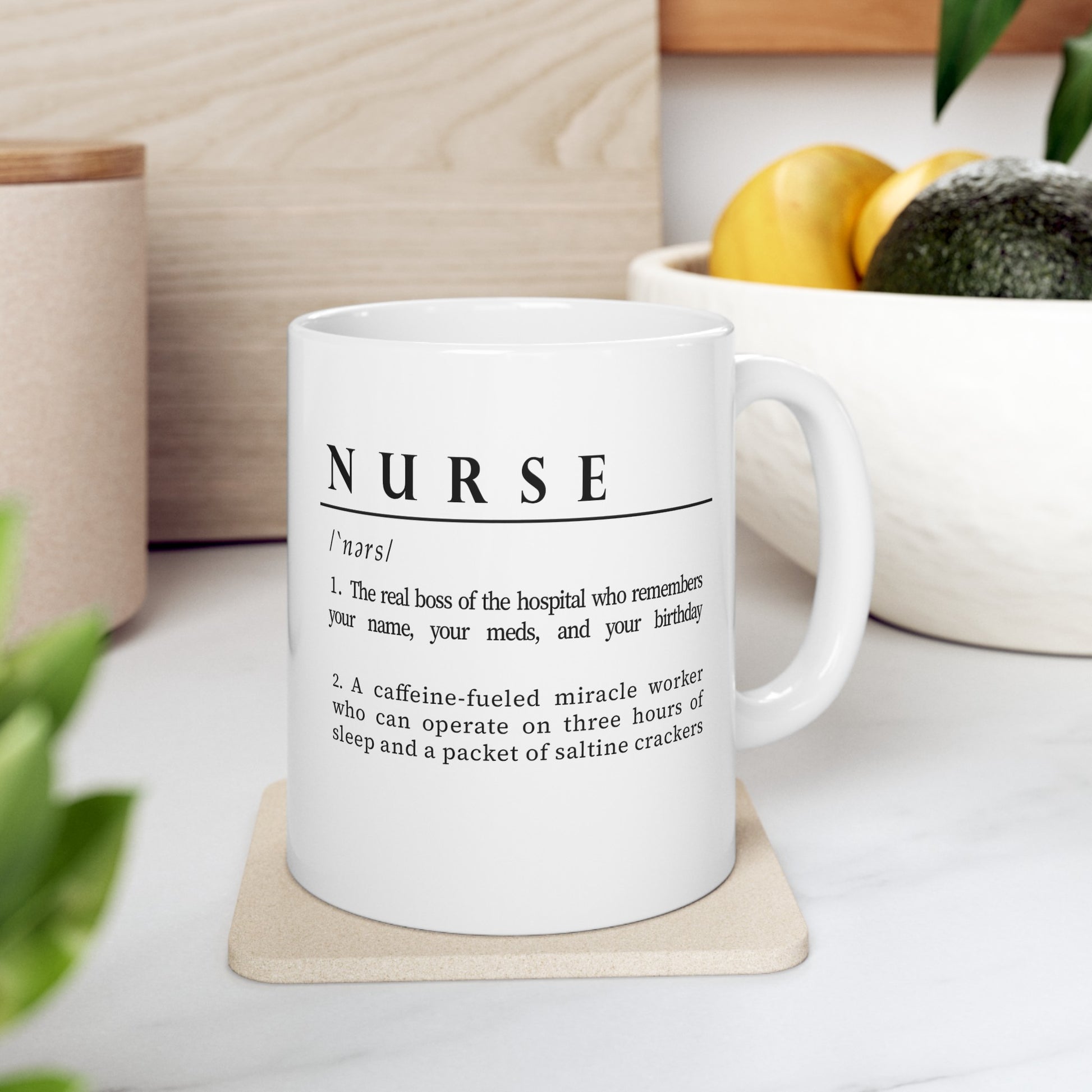 A white ceramic mug features a playful definition of 'Nurse' in black font. The humorous description portrays a nurse as both the caring boss of the hospital and a caffeine-powered miracle worker, highlighting their dedication and resilience.