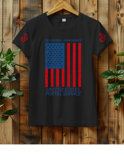 T-shirt hanging on a wooden wall with a hanger, displaying a distressed American flag graphic. The text "Delivering Honorably United States Postal Service" is printed in blue and red. The left sleeve has a red Marine Corps emblem. Two green plants are visible on either side of the shirt.