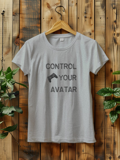 T-shirt with the text "CONTROL YOUR AVATAR" and an illustration of a game controller, hanging on a wooden wall. The scene is decorated with green plants on either side, creating a rustic and natural vibe