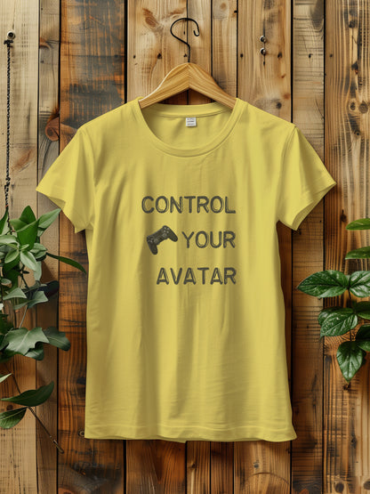 T-shirt with the text "CONTROL YOUR AVATAR" and an illustration of a game controller, hanging on a wooden wall. The scene is decorated with green plants on either side, creating a rustic and natural vibe