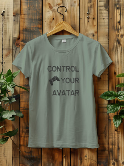 T-shirt with the text "CONTROL YOUR AVATAR" and an illustration of a game controller, hanging on a wooden wall. The scene is decorated with green plants on either side, creating a rustic and natural vibe