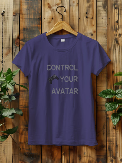 T-shirt with the text "CONTROL YOUR AVATAR" and an illustration of a game controller, hanging on a wooden wall. The scene is decorated with green plants on either side, creating a rustic and natural vibe