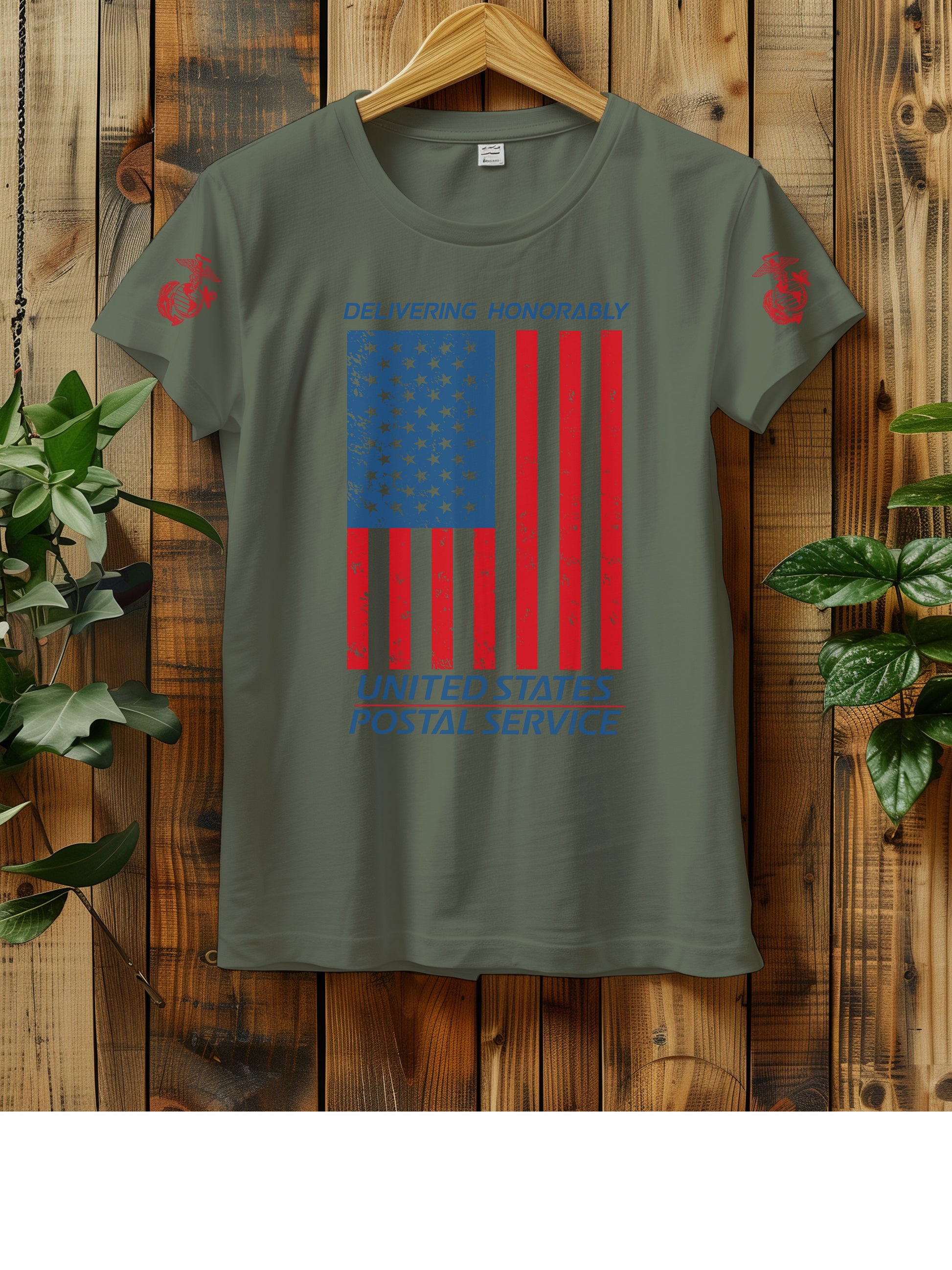 T-shirt hanging on a wooden wall with a hanger, displaying a distressed American flag graphic. The text "Delivering Honorably United States Postal Service" is printed in blue and red. The left sleeve has a red Marine Corps emblem. Two green plants are visible on either side of the shirt.