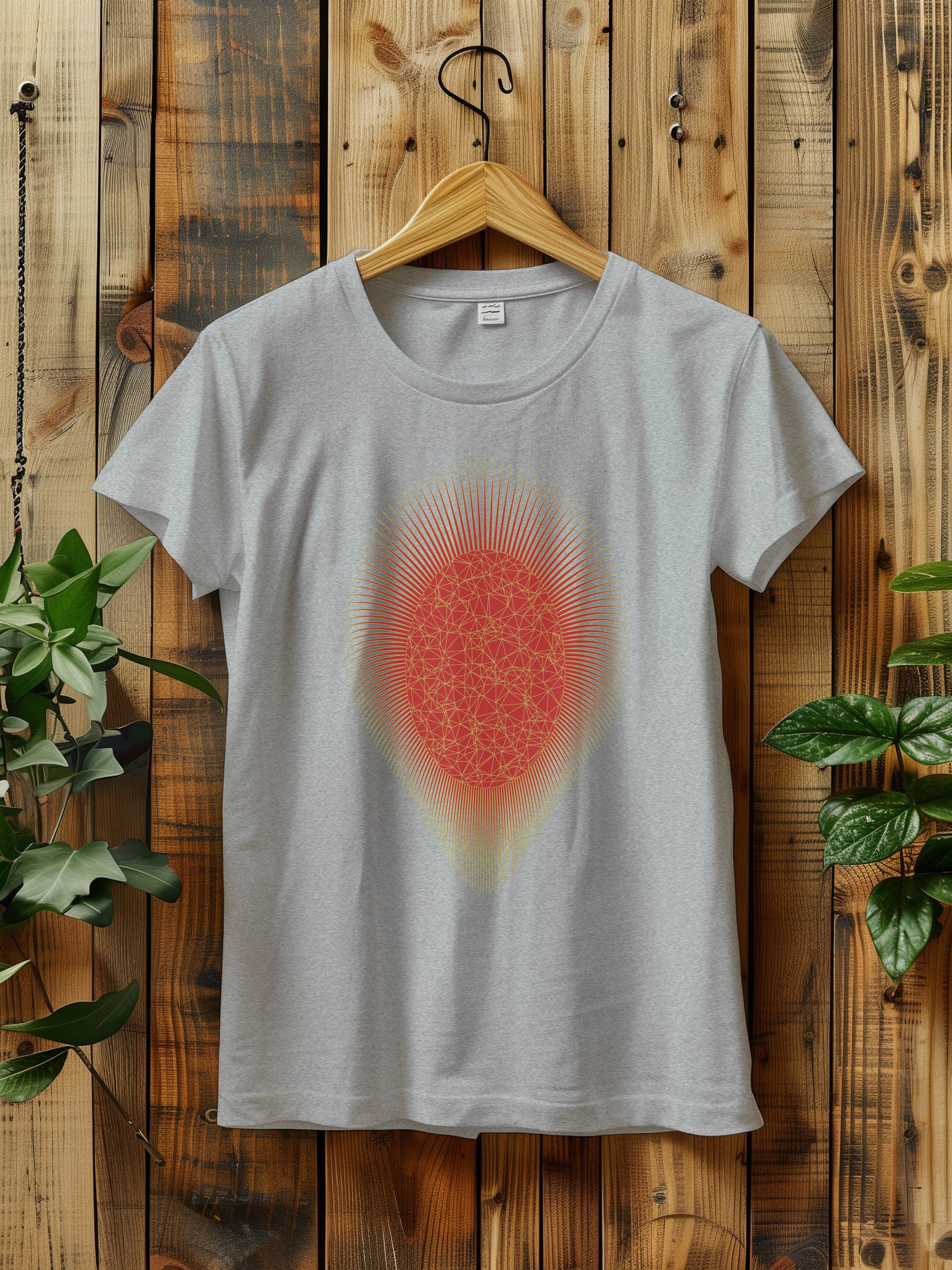 a t - shirt with a red and gold sunburst hanging on a wooden wall next to a plant