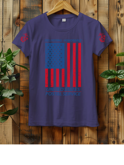 T-shirt hanging on a wooden wall with a hanger, displaying a distressed American flag graphic. The text "Delivering Honorably United States Postal Service" is printed in blue and red. The left sleeve has a red Marine Corps emblem. Two green plants are visible on either side of the shirt.