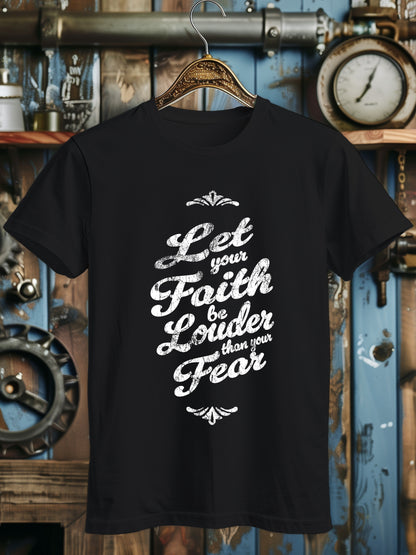 A T-shirt with the phrase Let your Faith be Louder than your Fear in decorative black script, displayed on a wooden hanger.