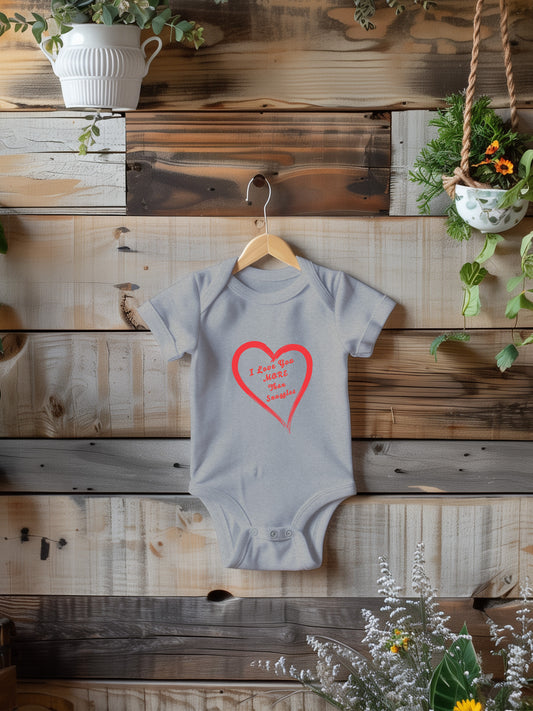 onesie with "I love you more than snuggles" in a heart on a wooden background with plants.