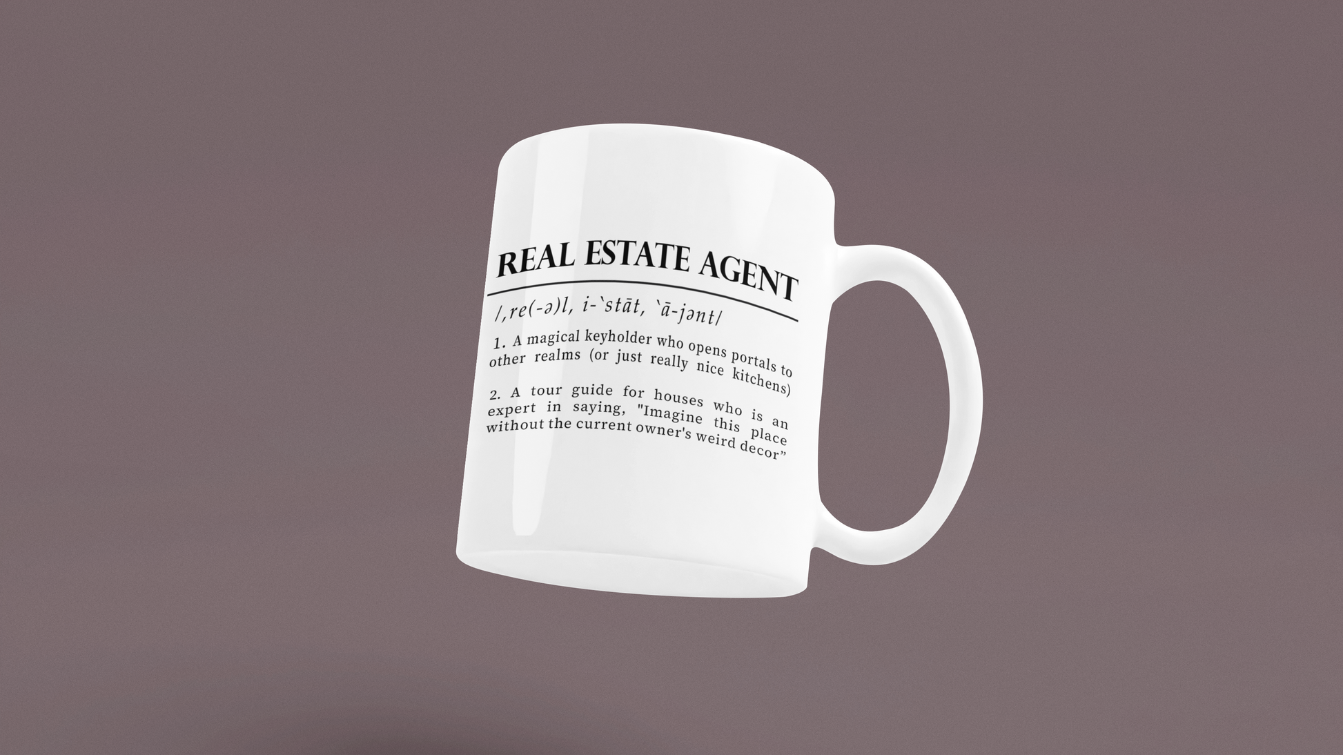 A classic white ceramic mug features a playful definition of 'Real Estate Agent' printed in elegant black font. The text humorously describes the agent as a keyholder to realms and an expert in home decor imagination. 